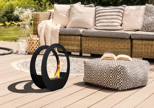 Pouf and rattan sofa on wooden patio with hanging chair in the garden. Real photo